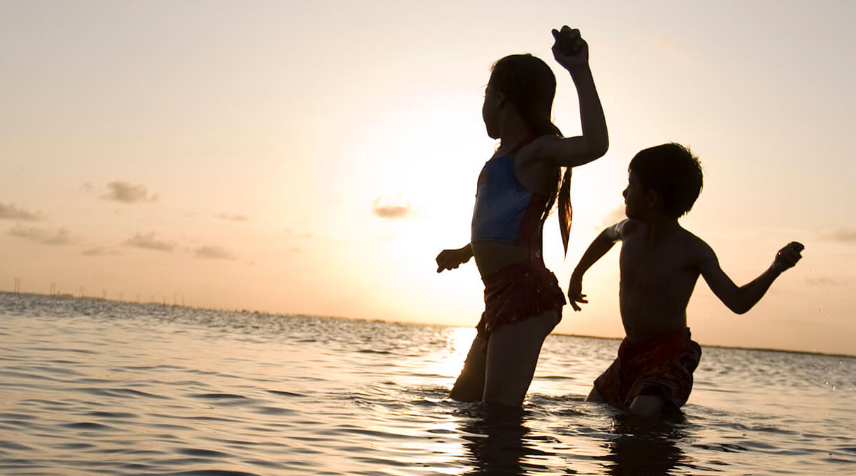 kids playing on the beach at sunset